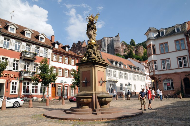 DSC_3792_1.jpg - Náměstí Kornmarkt, které mnozí považují za nejhezčí v celém Heidelbergu. Kašnu zdobí socha Madony z roku 1718, spočívající na bedrech andělů, která měla v období katolické protireformace obrátit protestanty zpět na pravou víru. V dnešní době toto půvabné dílo potěší nejen na pohled, ale i jako motiv na pohlednici jako „Madona obilného trhu se zámkem“.