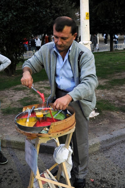 DSC_4871_1.jpg - Turecký med. Pod tímto pojmem si představíme typ, který  se připravuje z cukru, medu, vaječného bílku, vody a sekaných oříšků, který se u nás prodavá na poutích..... v Turecku je ale turecký med i barevný, tekutý a prodává se na dřevěném klacíku jako lízátko. Prodavač s ním dokáže divy, když ho namotává barvičku po barvičce.