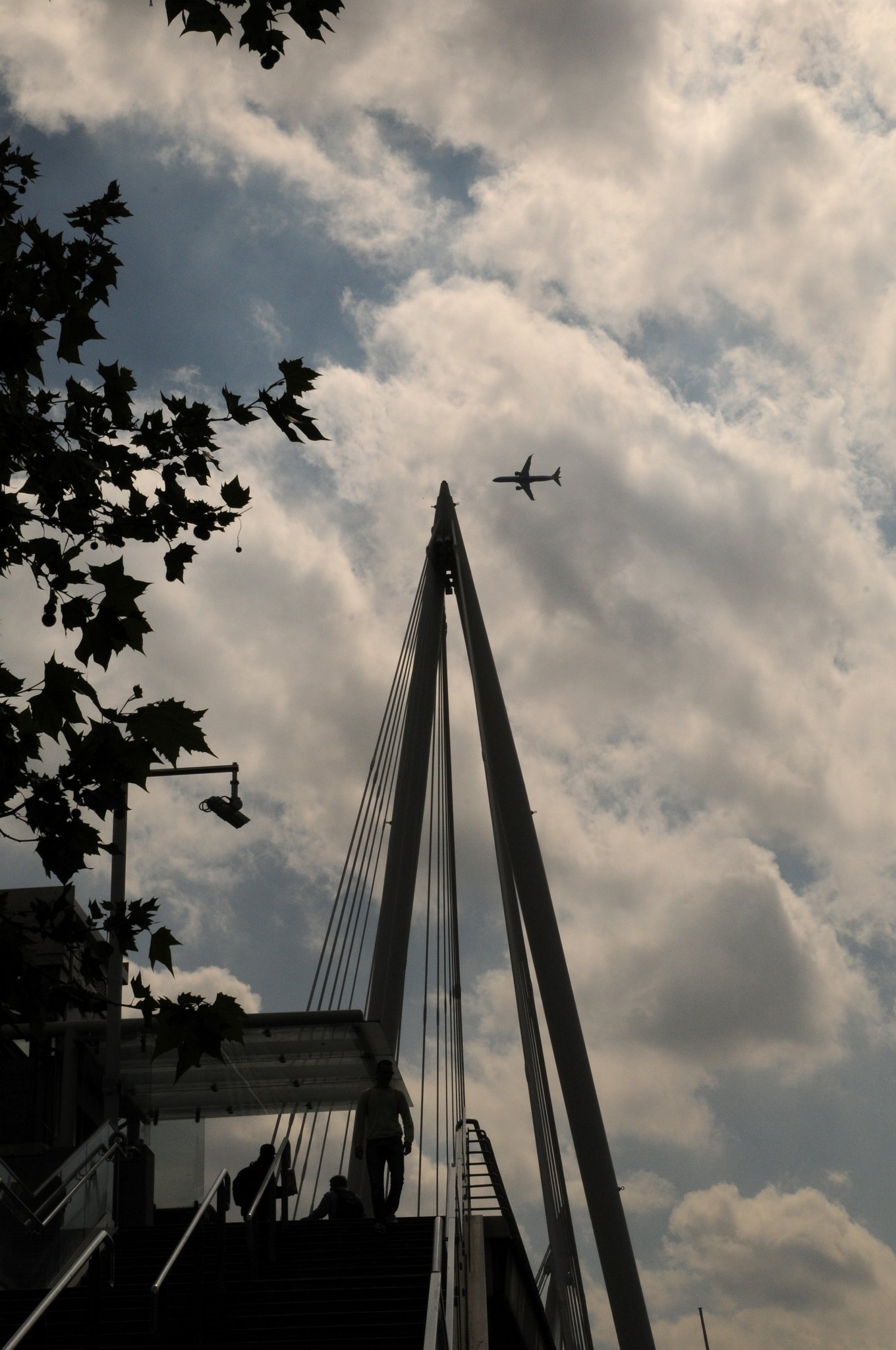 DSC_3866_2.jpg - Hungerford Bridge byl původně navržen Isambardem Kingdomem Brunelem jako visutý most pro pěší a byl otevřen roku 1845. Roku 1859 byl most zakoupen pro prodloužení South Eastern Railway do nově vybudovaného nádraží Charing Cross. Společnost provozující tuto železnici nahradila původní visutý most konstrukcí navrženou Johnem Hawkshawem sestávající z devíti oblouků z tvářené oceli. Řetězy z původního mostu byly použity pro Clifton Suspension Bridge v Bristolu. Původní cihlové opěrné pilíře jsou stále používány i když pilíř u Charing Cross se nachází blíže břehu z důvodu výstavby Victoria Embankment (ukončené roku 1870). U pilíře na straně u jižního nábřeží se dochovaly vchody a schody postavené pro původní visutou lávku pro pěší.