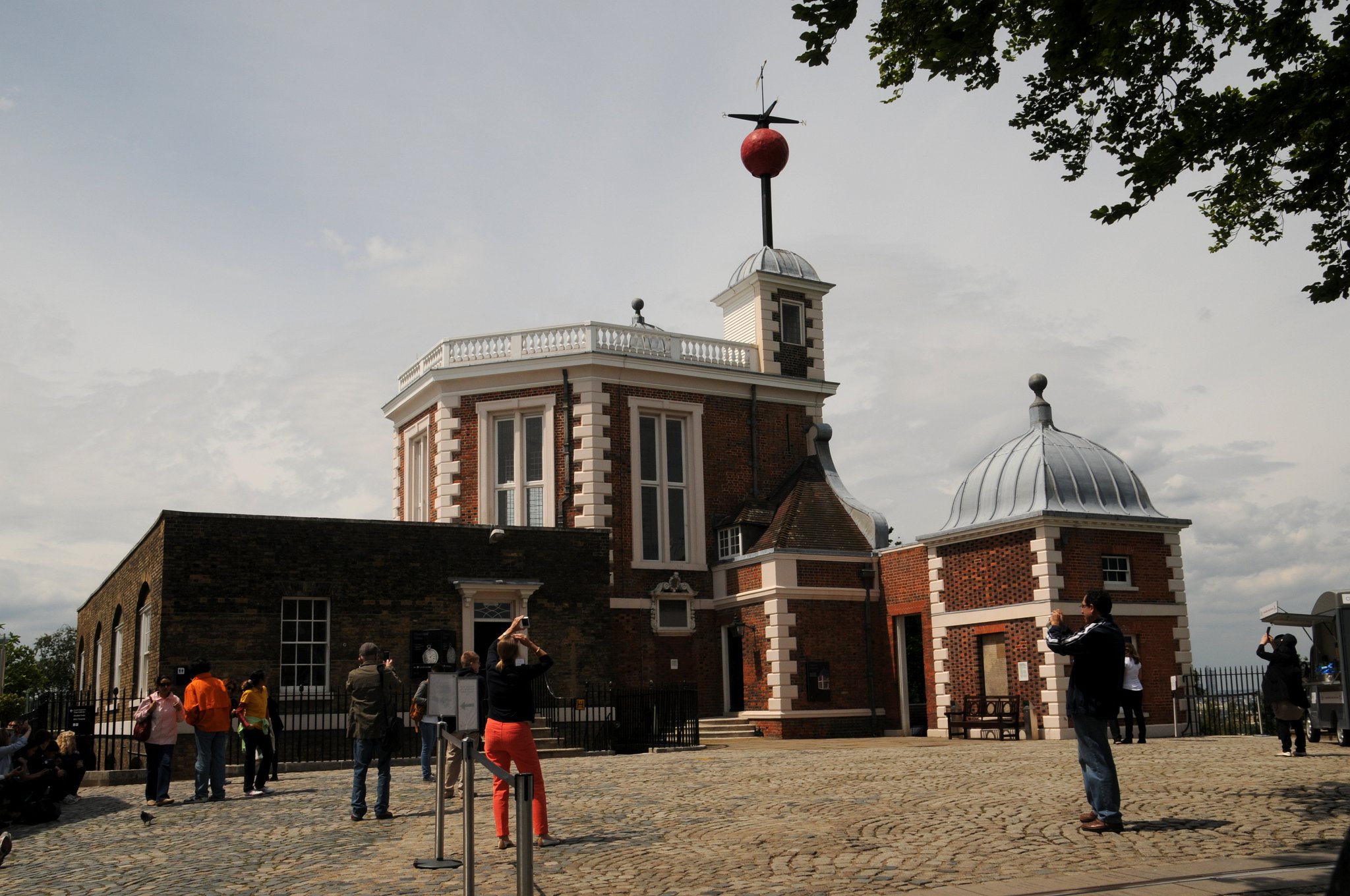 DSC_4115_2.jpg - Královská greenwichská observatoř (anglicky původně Royal Greenwich Observatory) byla zřízena roku 1675 králem Karlem II. V té době byl také zřízen úřad královského astronoma, aby řídil práci observatoře a podporu navigace. Nachází se na kopci v Greenwich Parku v londýnském obvodu Greenwich. Britští astronomové používali observatoř pro svá měření dlouhou dobu. Budovou vedly čtyři poledníky. Základem pro měření zeměpisné polohy byl nultý poledník ustanovený roku 1851 a přijatý na mezinárodní konferenci roku 1884. Původně byla jeho poloha vyznačena na dvoře observatoře mosazným páskem, později nahrazen páskem z nerezové oceli a od 16. prosince 1999 silným zeleným laserovým paprskem osvětlujícím londýnské noční nebe.
