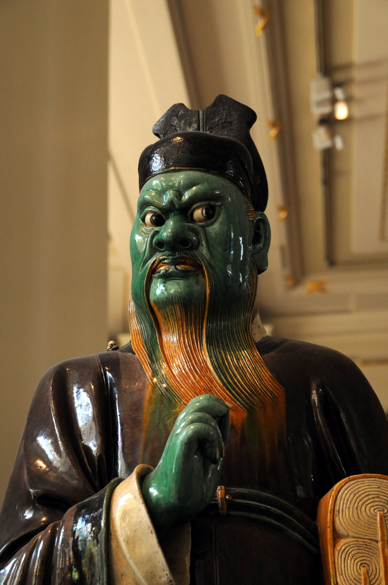 DSC_5952_2.jpg - Kameninová figura v barvě lilkové, zelené a okrové, glazovaná. Dynastie Ming, 16. století našeho letopočtu.Víra v peklo přišla do Číny s buddhismem v začátku 1.tisíciletí našeho letopočtu. Od konce dynastie Tang byly výjevy z podsvětí bežné. Tato figura soudce drží pod levou paží záznamy o zlých skutcích.