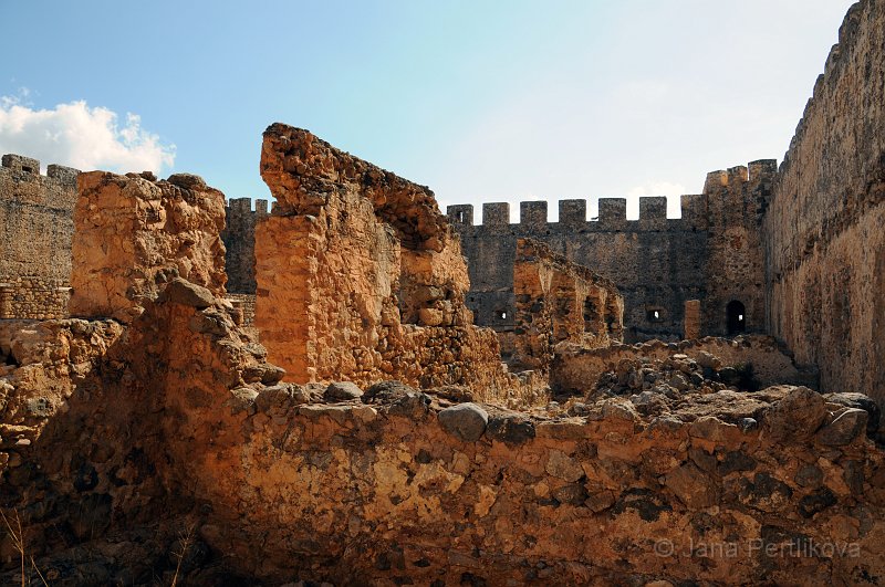 DSC_8328_1.jpg - Před hradem stojí pomník krétských bojovníků s jejich vůdcem Chatsimichálisem.Skutečné strašidelné postavy "Drossoulites" se v těchto kulisách potkávají každý rok v květnu. Pověrčivý člověk může věřit příběhu, že za svítání tady putují stíny duší krétských bojovníků odporu, kteří jsou zde od roku 1828 pohřbeni na pobřeží v písku. Říká se jim „muži rosy”. Nejste-li pověrčiví, uvěříte spíše vědcům, kteří tvrdí, že stíny jsou zrcadlením vzduchu z Libye (Fata Morgana). Ten se vyskytuje pouze v květnu a za specifických klimatických povětrnostních podmínek. Tyto úkazy můžete vidět každý rok (s několika výjimkami) znovu a znovu.