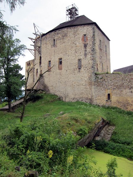 IMG_0875_1.jpg - Točník patří mezi nejmladší, ale rozlohou největší hrady v Čechách. Do hradu se vstupovalo od východu po mostě, podpíraném dvěma pilíři, nad hlubokým a širokým příkopem, vylámaným ve skále. Na jeho dně byla vyhloubena cisterna, v níž byla zachycována dešťová voda. Cisterna byla jediným zdrojem vody pro hrad až do první poloviny 16. století
