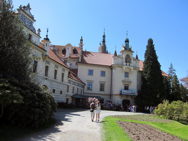 IMG_6438_1.jpg -                                Na místě dnešního zámku vybudovali ve 14. století gotickou tvrz se statkem páni z Říčan. Tvrz byla v jejich vlastnictví až do 90. let 14. století, kdy se stala majetkem měšťanů z Prahy. Velké nádvoří Průhonického zámku. Z nádvoří se nám naskýtá pohled na románský kostelík, levé křídlo zámku zvané Malý zámek s novorenesančními štíty a sgrafity a průčelí hlavní zámecké budovy.