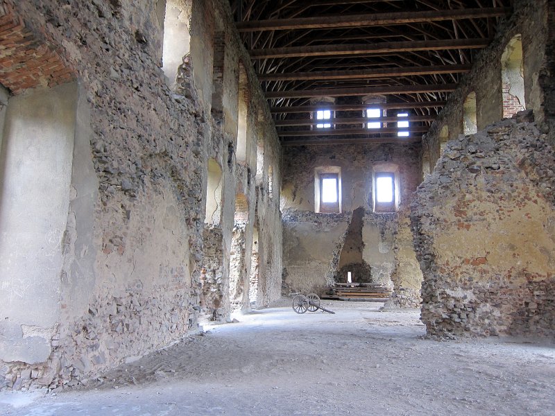 IMG_0942_1.jpg - Přestože vnitřní palác byl rozsáhlý a kromě toho byla mezi ním a hradební zdí dodatečně postavena ještě další gotická obytná budova, nemohl postačit účelům, pro něž byl hrad Točník postaven. Proto byl na druhém nádvoří postaven druhý palác. Purkrabský (velký) palác, tvořící západní část hradu. Do přízemí této budovy, kde byly konírny, se vstupovalo na severovýchodní straně přímo z nádvoří. Palác měl dvě patra a podkroví. V prvním patře paláce byly dva sály s užší vstupní síní uprostřed, druhé patro tvořil jediný rozsáhlý sál s mohutným krbem. V podkroví byly komůrky pro služebnictvo a hradní posádku. Palác byl kryt sedlovou střechou. K tomuto paláci přiléhalo na jihozápadní straně příčné jednopatrové křídlo, které se táhlo až k věžovité stavbě uzavírající na západní straně parkán obytného jádra hradu.